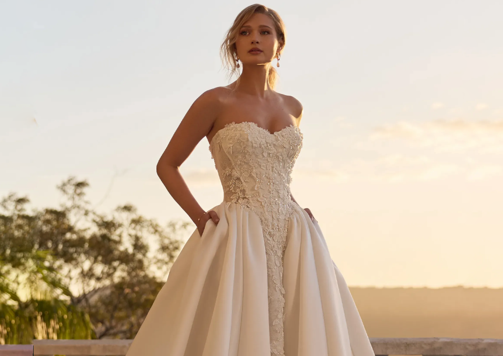Model wearing a white gown by Sophia Tolli