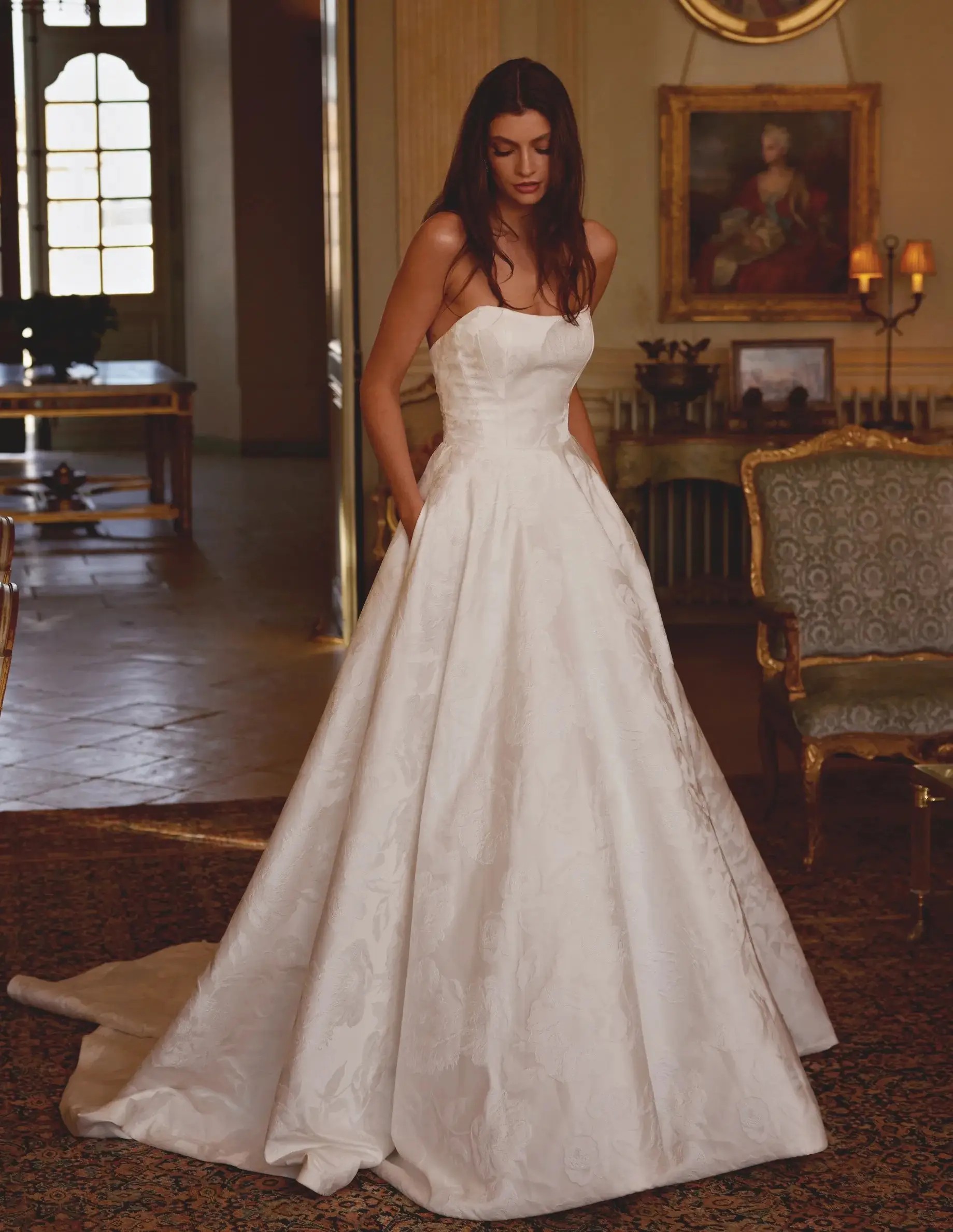 Brunette woman wearing a long sleeve stretch mikado fit and flare with cutout lace train wedding