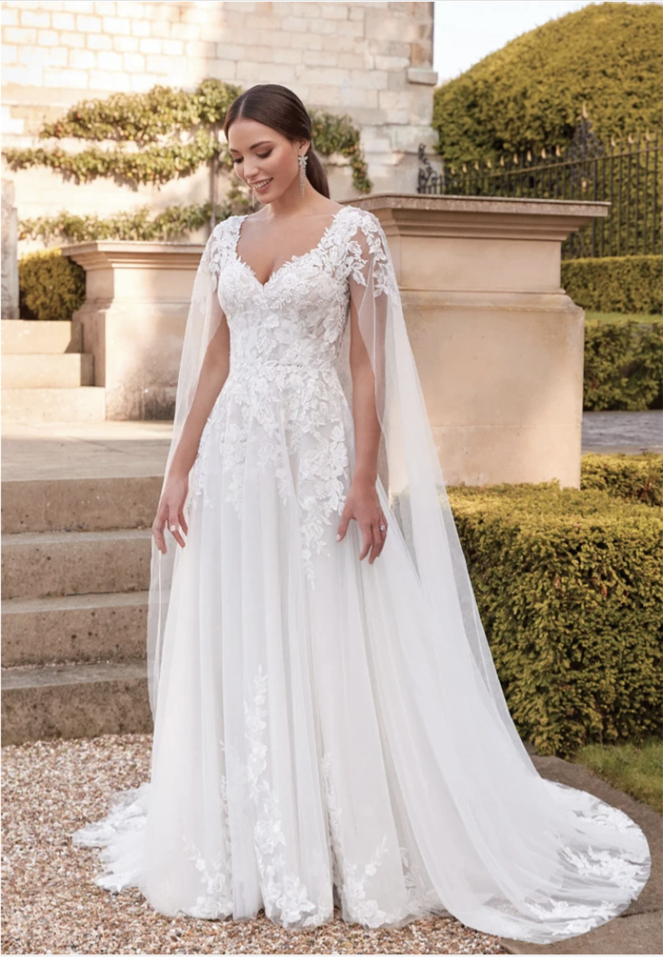Brunette woman wearing a v-neck flower wedding gown with detachable long tulle cape sleeves