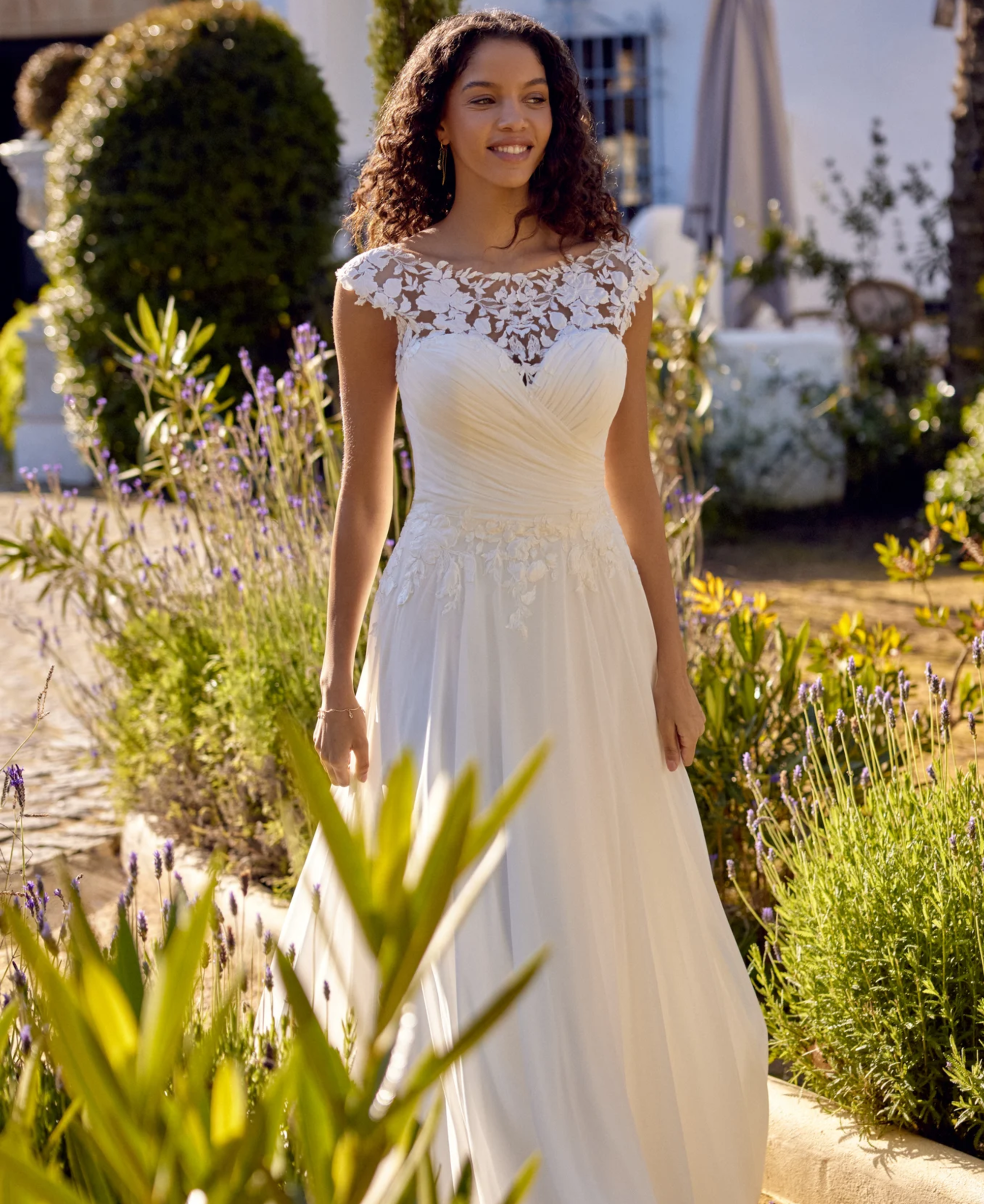 Woman with curly hair wearing lace illusion neckline bridal dress