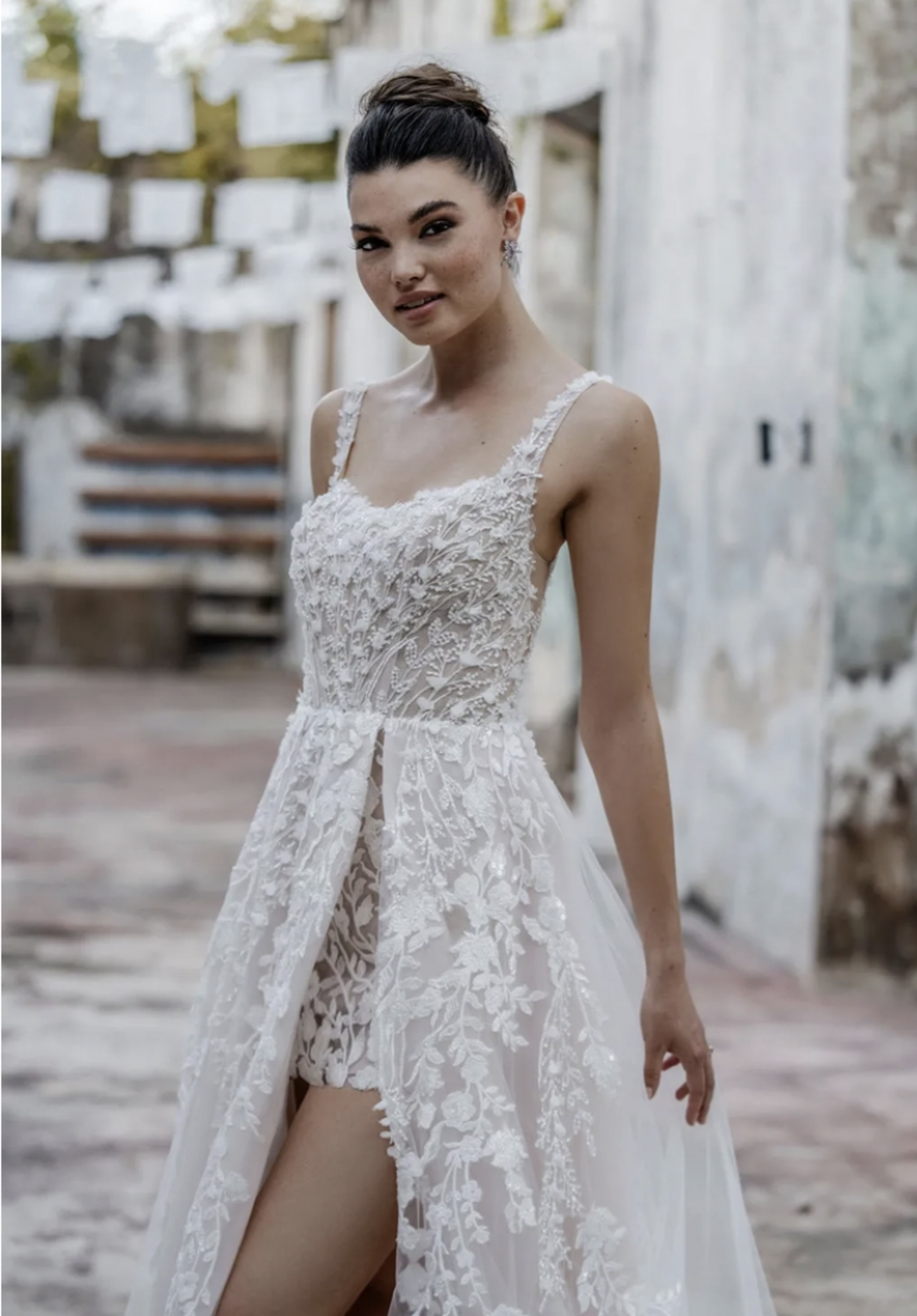 Brunette woman with hair in a bun wearing flower wedding dress